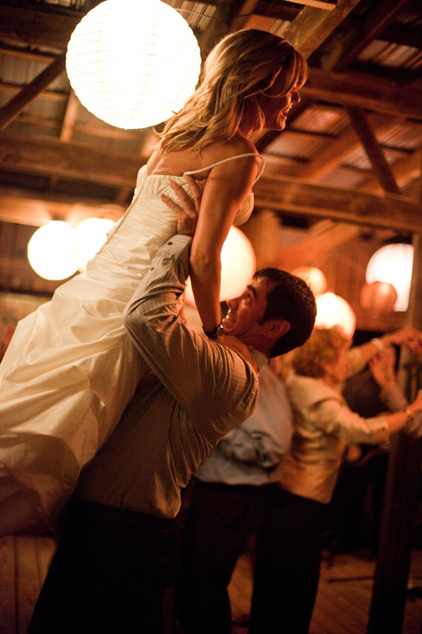 Groom holding bride up in the air while dancing at reception - photo by North Carolina based wedding photographer Jeremie Barlow